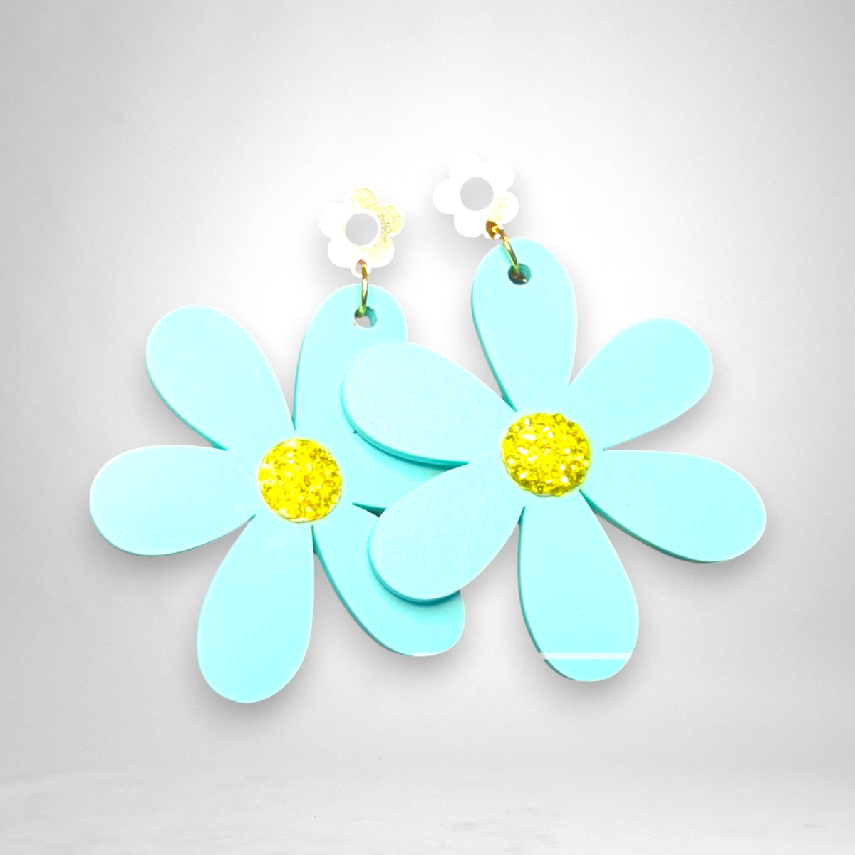 12th Ave Design Co. light blue acrylic flower earrings with yellow crystal centers and white daisy stud toppers.