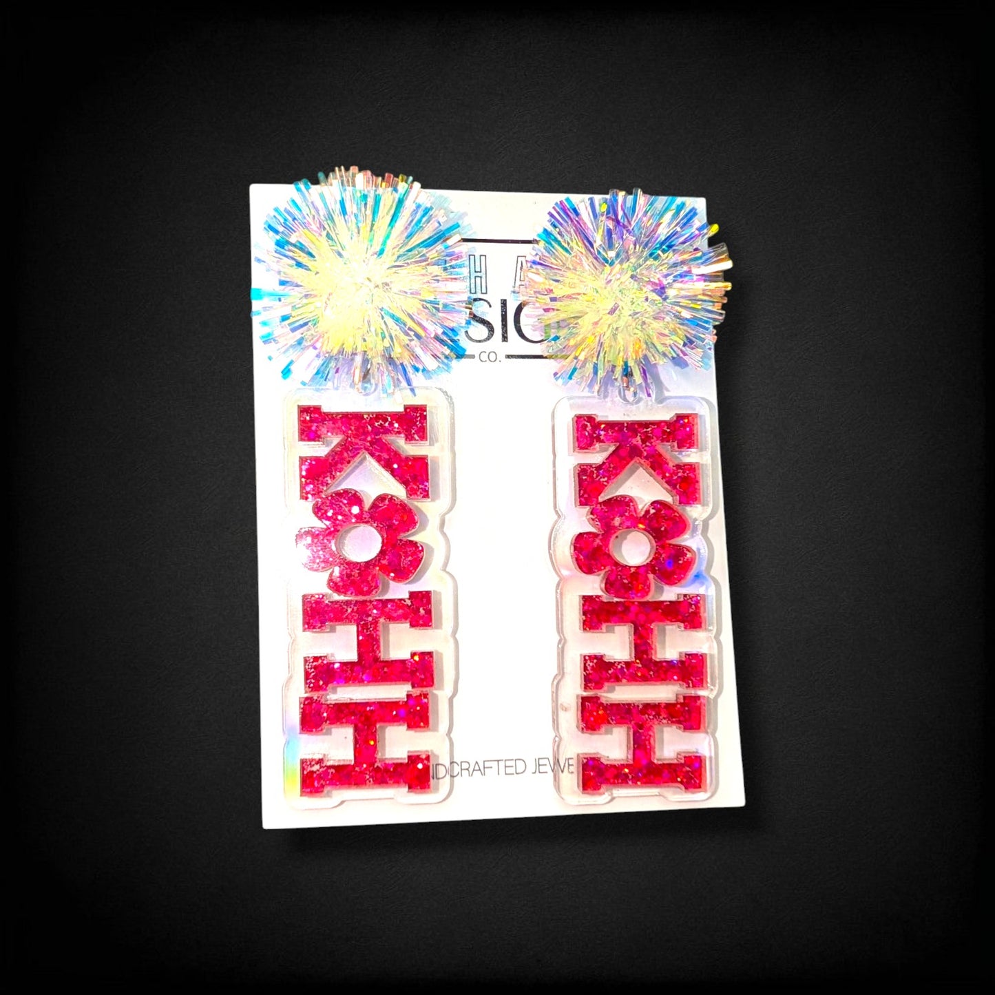 12th Ave Design Co. KOHH Varsity Bloom earrings featuring iridescent pom-poms and pink glitter acrylic lettering.