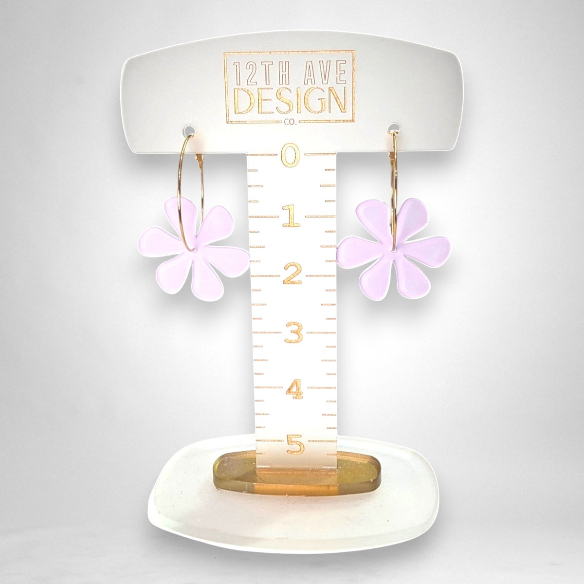 12th Ave Design Co. floating daisy hoop earrings featuring light purple acrylic flower charms on gold-plated hoops.