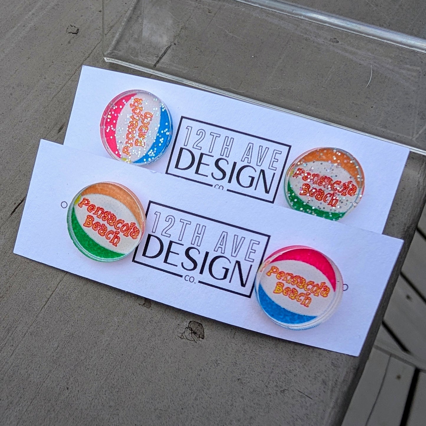 Colorful stud earrings with 'Pensacola Beach' text on a beachball design