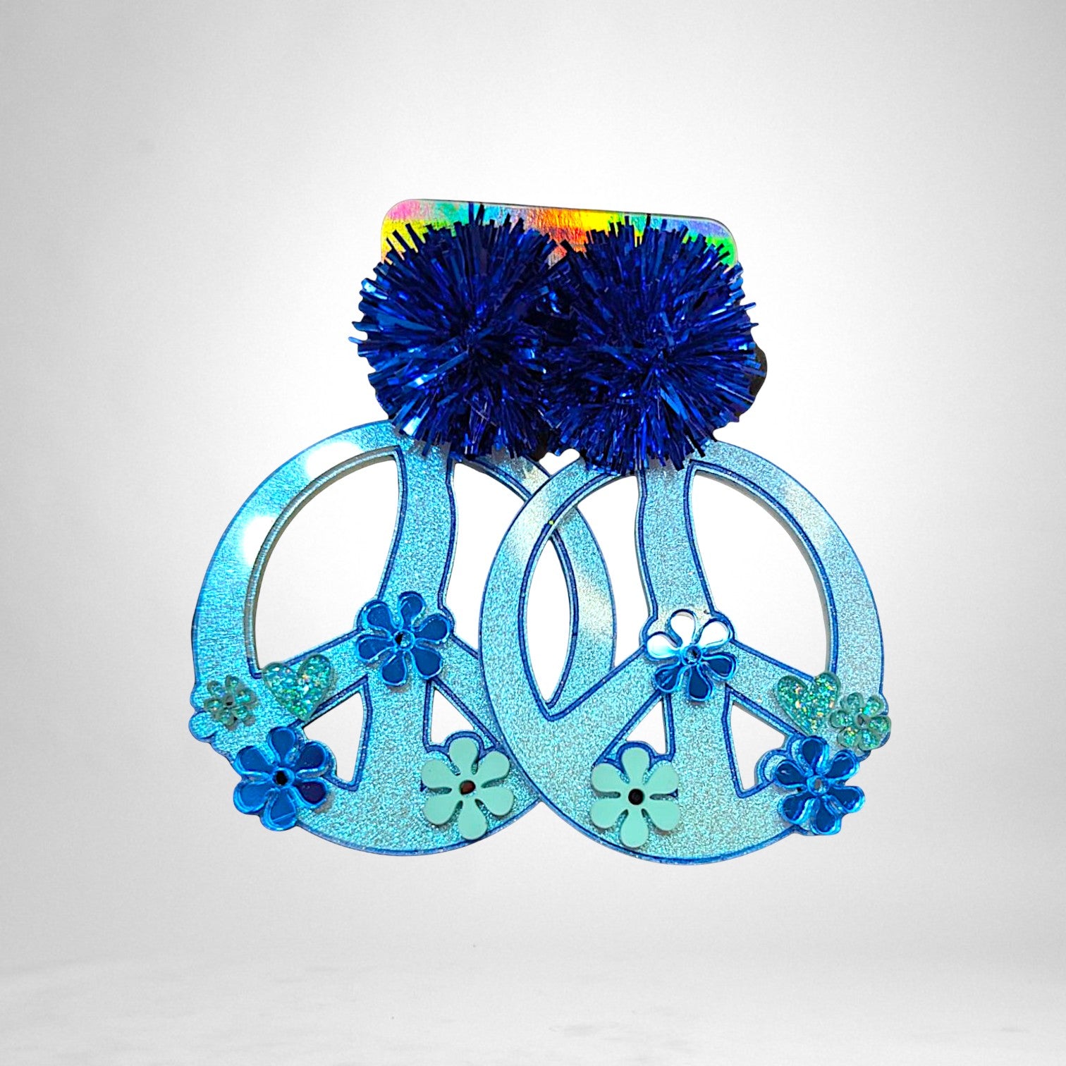 12th Ave Design Co. custom blue peace sign earrings featuring glittery finish, floral accents, and blue pom-poms.