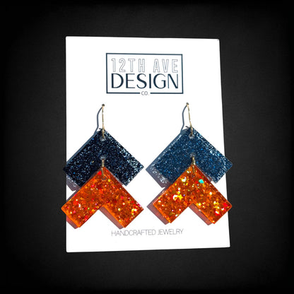 12th Ave Design Co. chevron drop earrings featuring glittery navy blue and orange resin on surgical steel hooks.