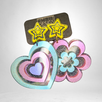 12th Ave Design Co. custom mismatched acrylic earrings featuring a glittery heart and flower design with star studs.