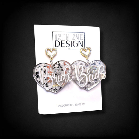 12th Ave Design Co. custom heart-shaped disco ball earrings with Bride text and rhinestone accents on display card