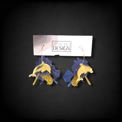 12th Ave Design Co. custom dolphin earrings featuring blue resin, gold glitter accents, and gold hoop connectors.