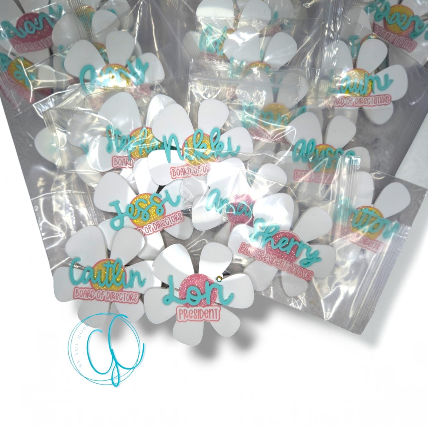 12th Ave Design Co. custom flower-shaped acrylic nametags with glitter accents and personalized names in plastic bags.