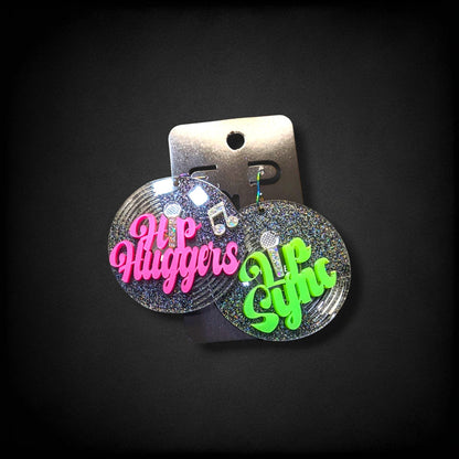 12th Ave Design Co. custom glittery circular earrings featuring neon pink and green text on a black background