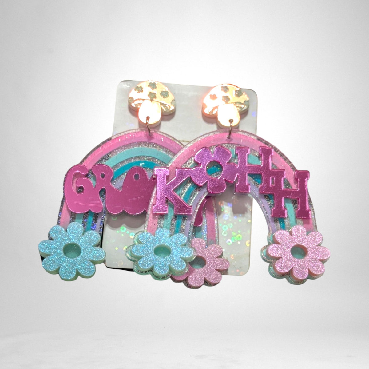 12th Ave Design Co. custom KOHH acrylic earrings featuring glittery rainbows, flowers, and mushroom studs.