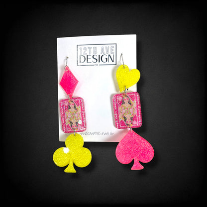 12th Ave Design Co. custom glittery playing card earrings featuring neon pink and yellow suit shapes.