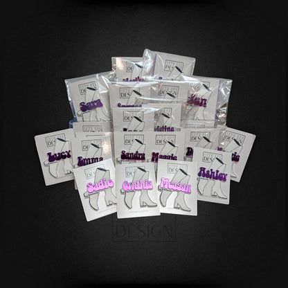 12th Ave Design Co. custom purple acrylic boot-shaped nametags in individual packaging on a black background.