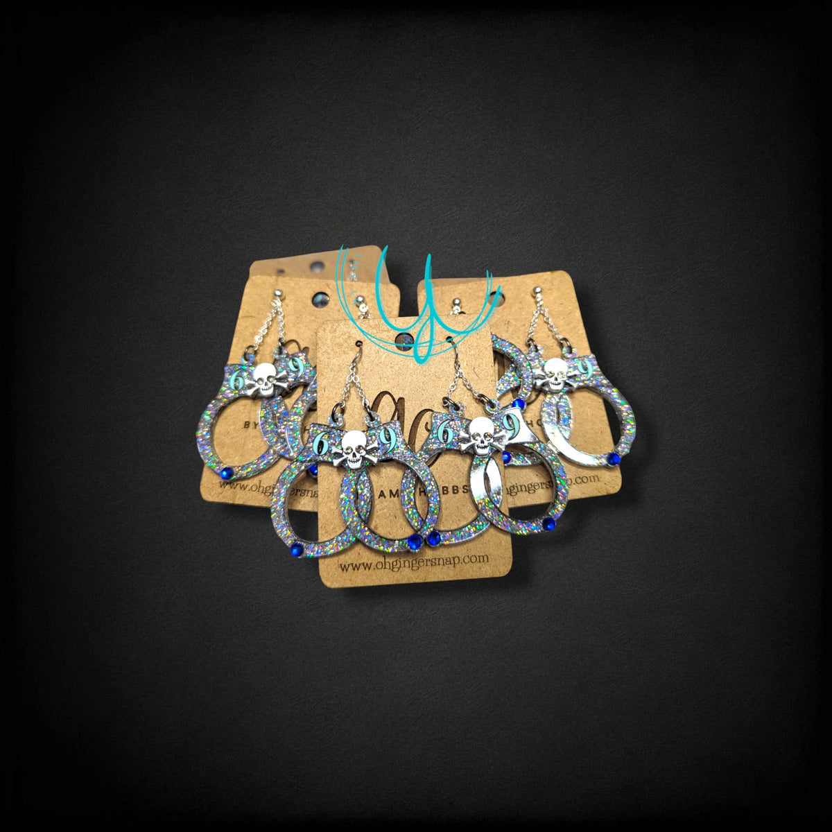 12th Ave Design Co. custom glittery skull earrings with blue accents on display cards for special events.