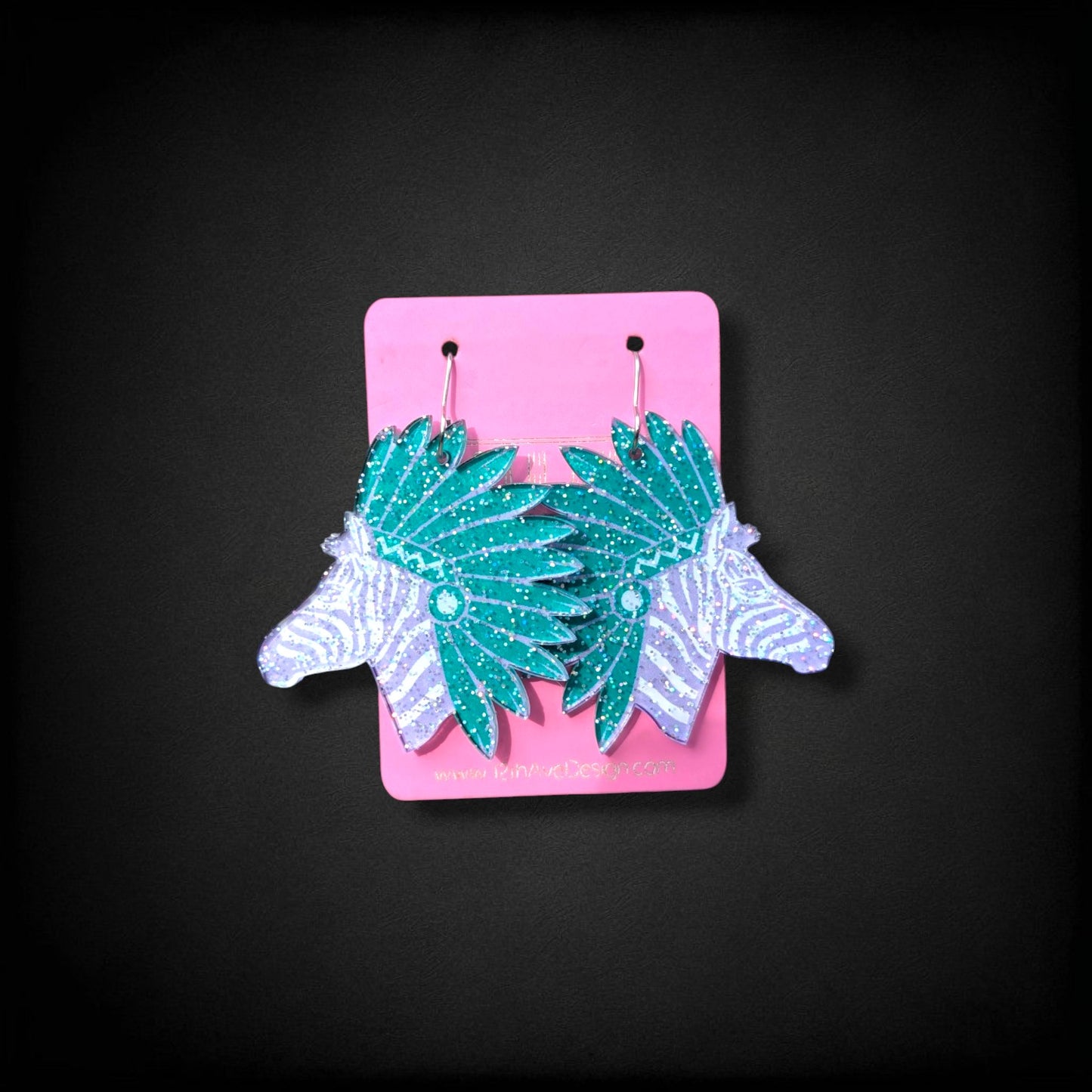 12th Ave Design Co. custom glittery teal and white zebra head earrings with headdress detail on a pink display card