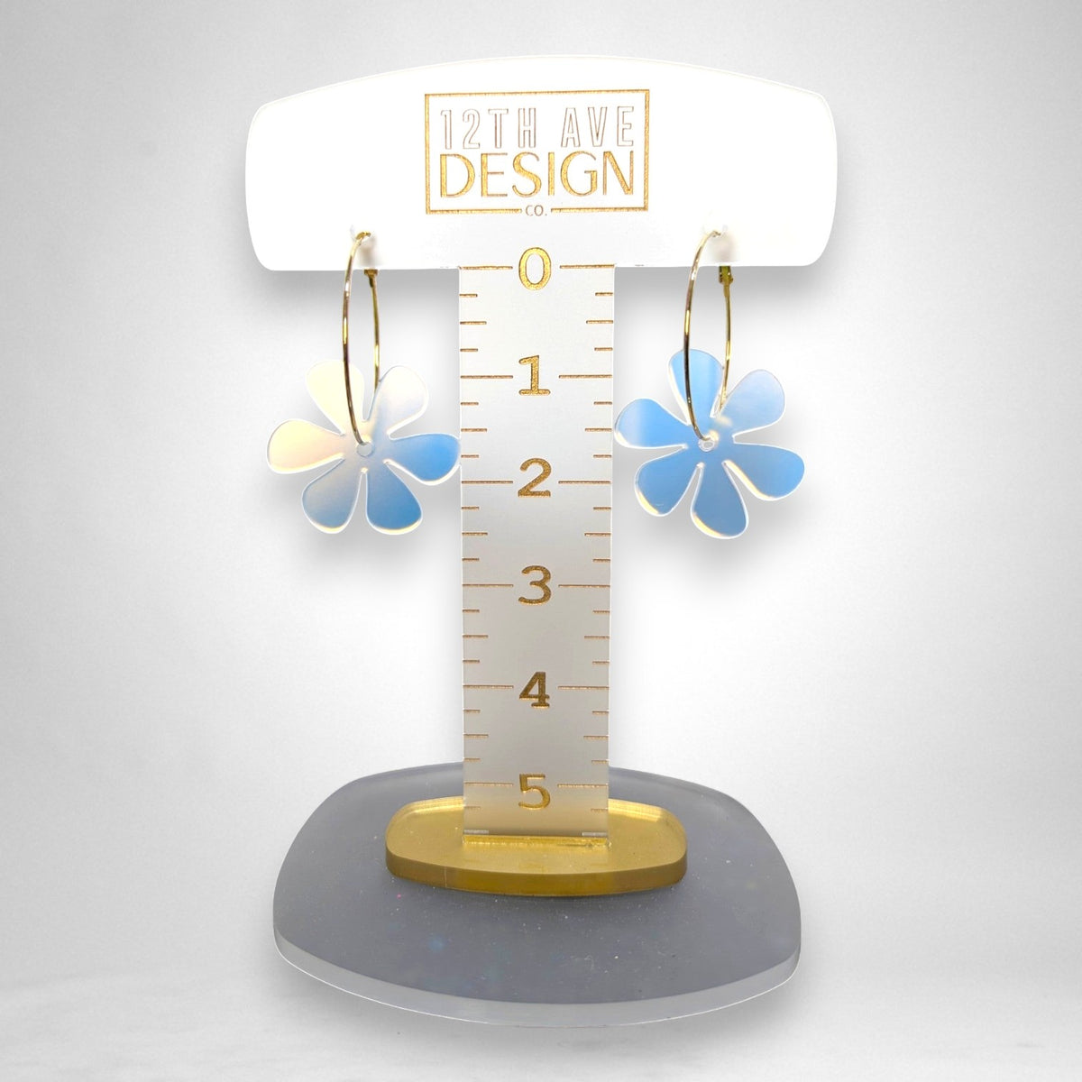 12th Ave Design Co. floating daisy hoop earrings with iridescent acrylic flower charms on gold-plated hoops.