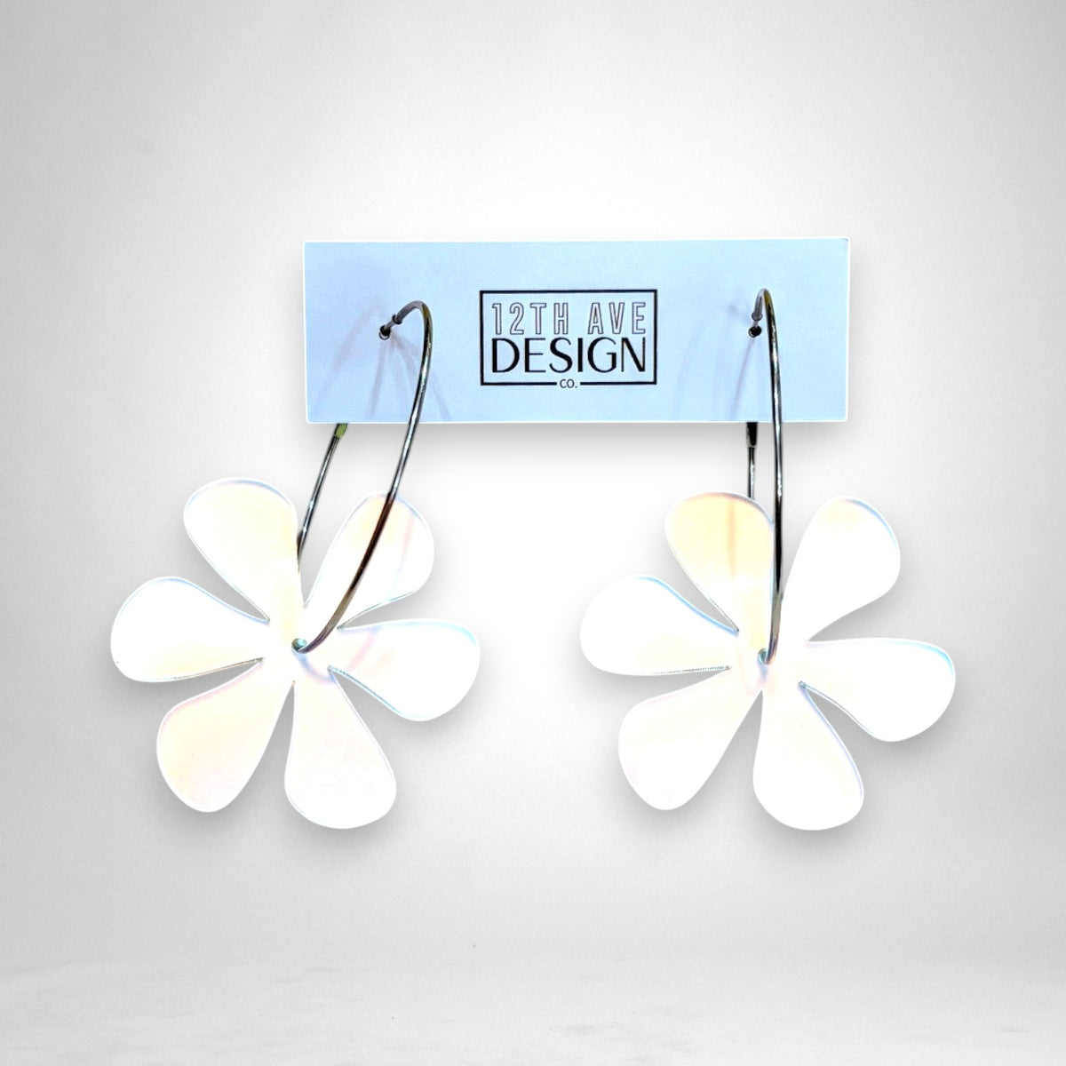 12th Ave Design Co. floating daisy hoop earrings featuring white acrylic flower charms on silver stainless steel hoops