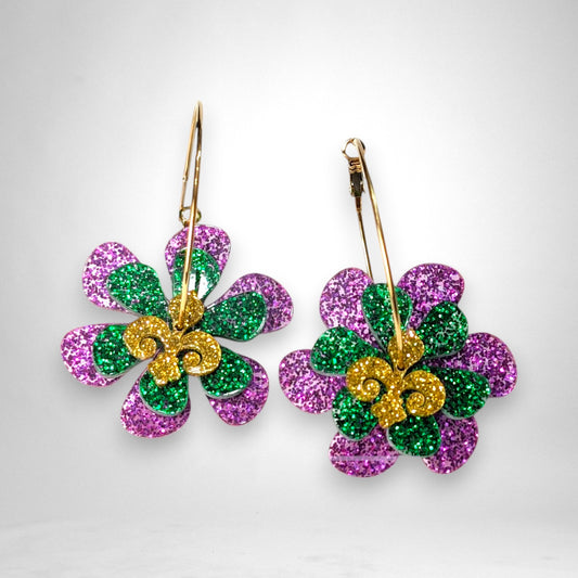 12th Ave Design Co. glittery purple, green, and gold acrylic flower hoop earrings on a black background.