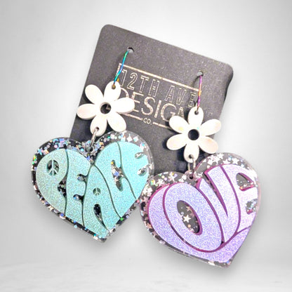 12th Ave Design Co. heart-shaped acrylic earrings with glitter, daisy accents, and groovy Peace and Love lettering.