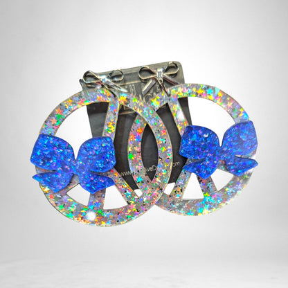 12th Ave Design Co. custom peace sign earrings featuring holographic glitter finish and blue glitter bow accents.
