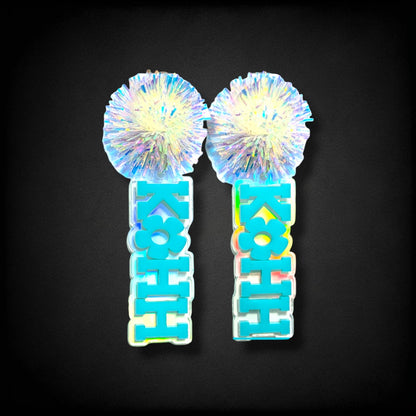 12th Ave Design Co. KOHH Varsity Bloom earrings featuring iridescent pom-poms and engraved blue acrylic lettering.
