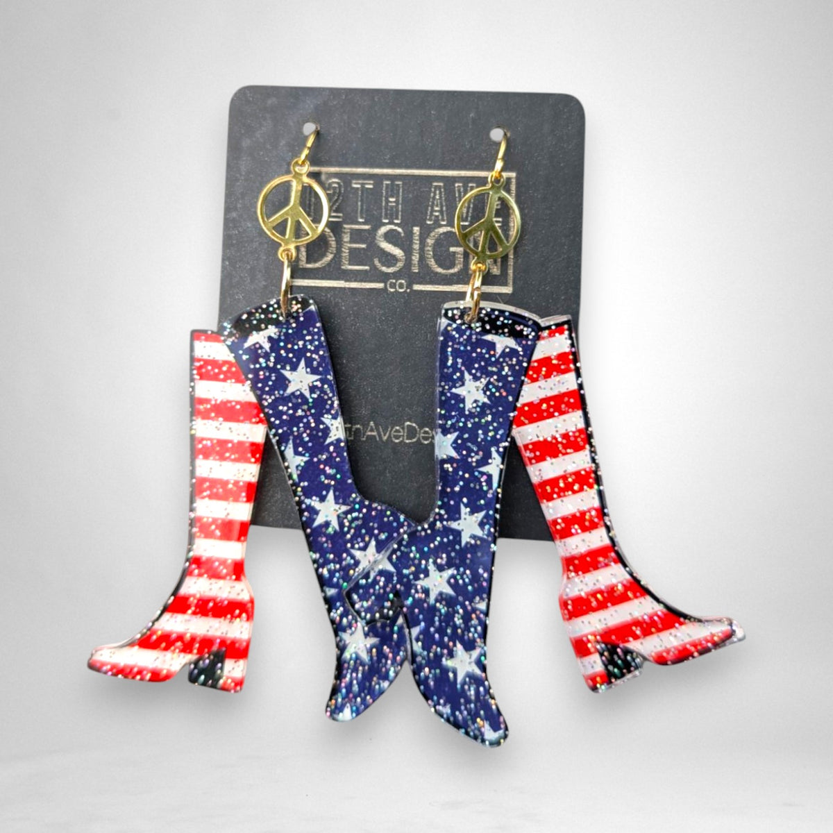 12th Ave Design Co. patriotic go-go boot earrings with US flag print, gold peace sign charms, and mini-hooks.