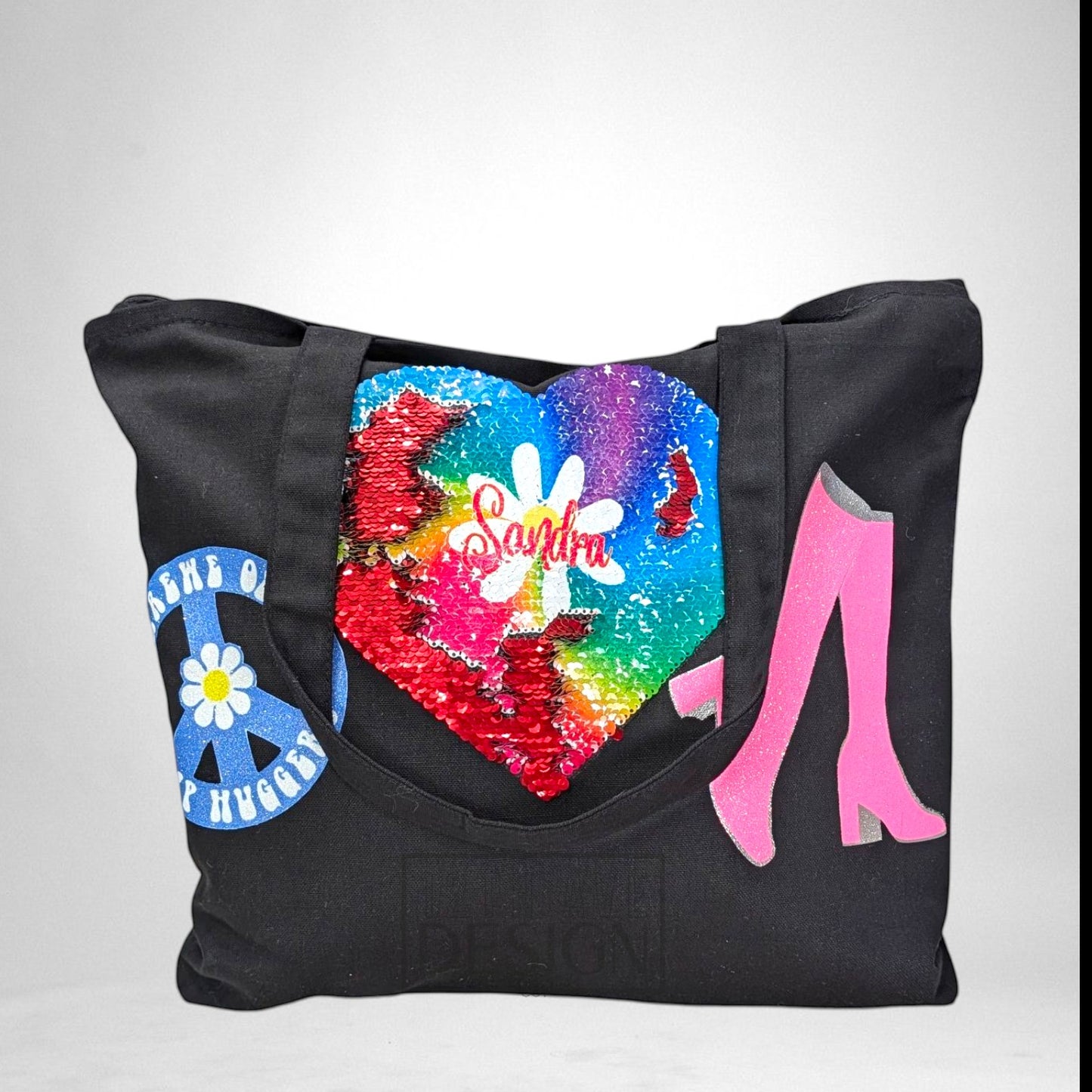 12th Ave Design Co. black canvas tote bag featuring a rainbow sequin heart, peace sign, and pink boot patches.