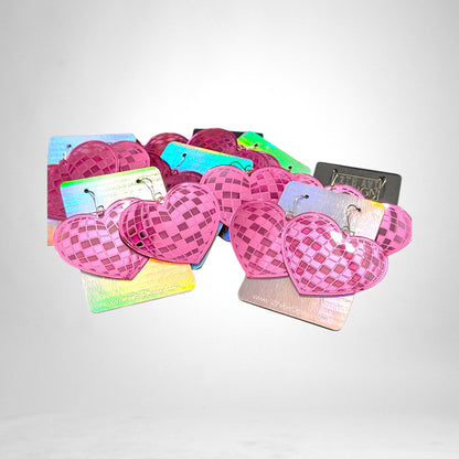 12th Ave Design Co. pink heart-shaped disco ball earrings with a reflective checkered pattern on display cards.