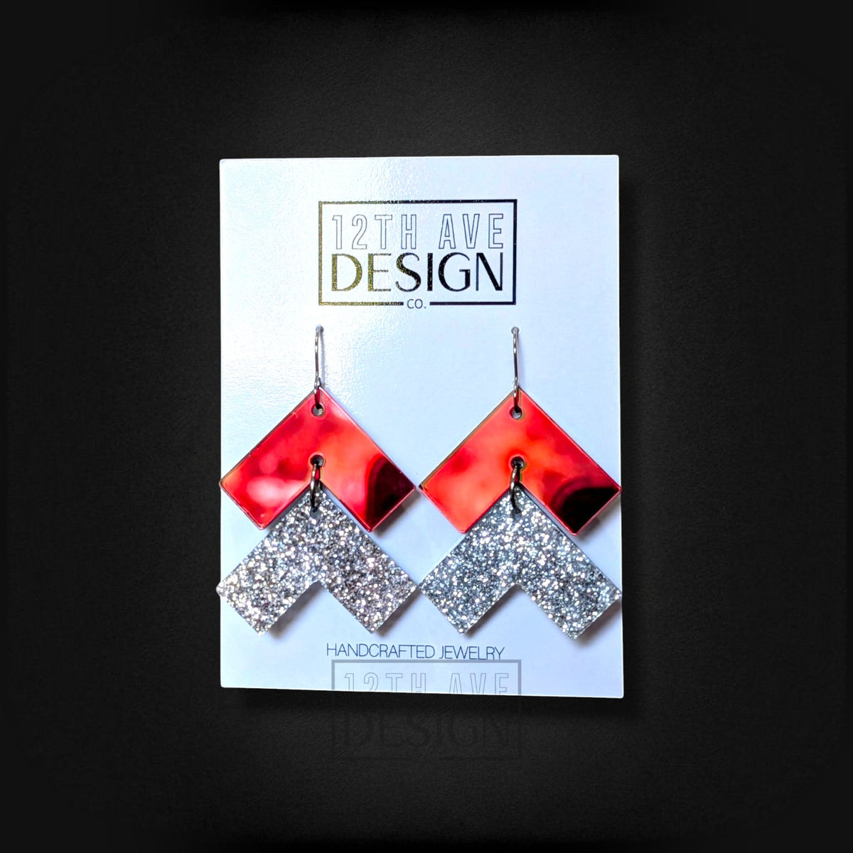 12th Ave Design Co. chevron drop earrings featuring red mirrored and silver glitter geometric shapes on steel hooks.