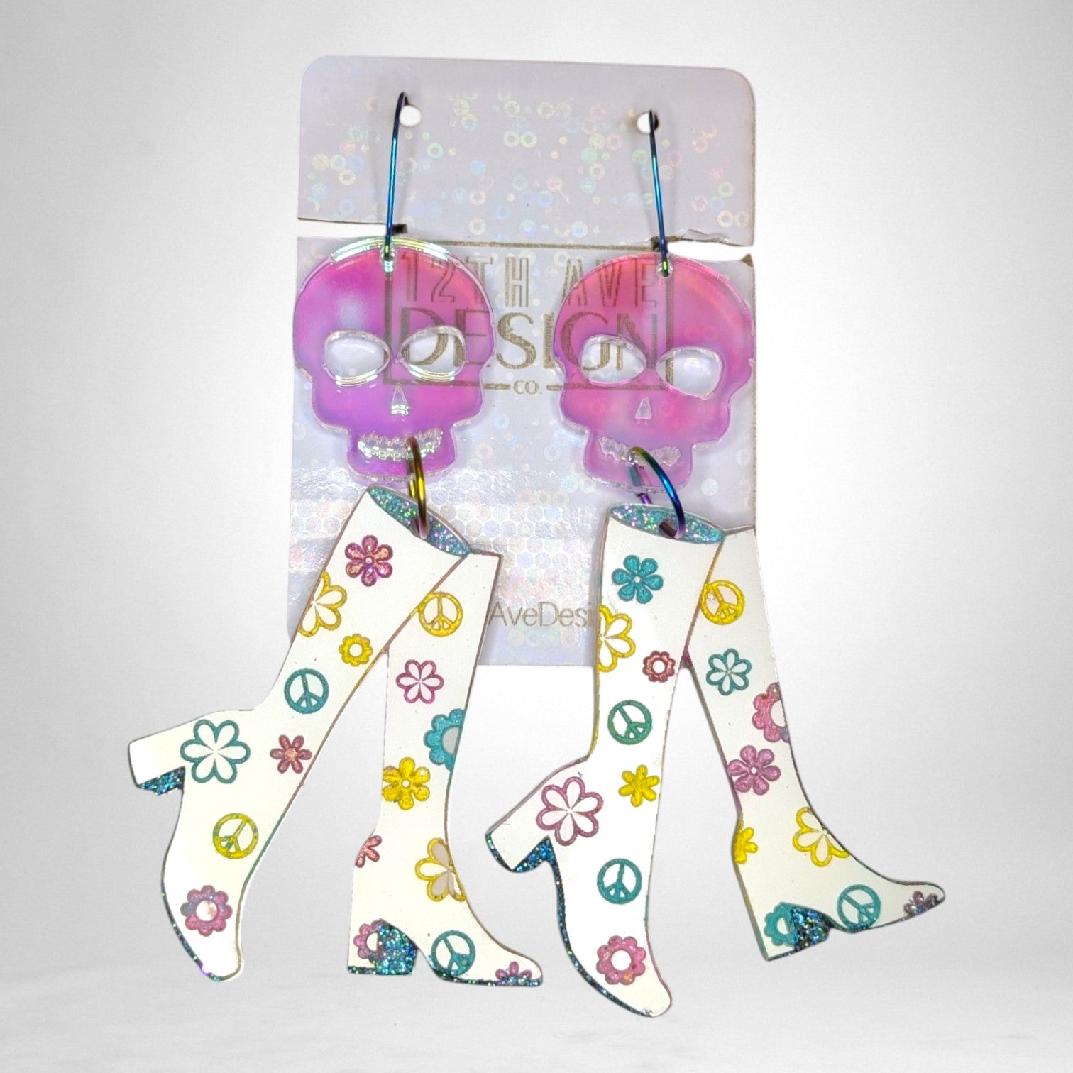 12th Ave Design Co. custom earrings featuring pink translucent skull tops and white go-go boots with floral patterns.