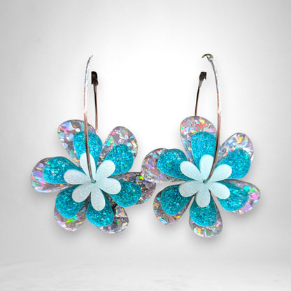12th Ave Design Co. floating daisy hoop earrings featuring layered teal glitter and iridescent acrylic flowers.