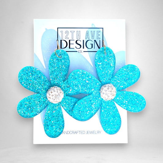 12th Ave Design Co. statement floral earrings in bright turquoise glitter acrylic with crystal-encrusted centers.