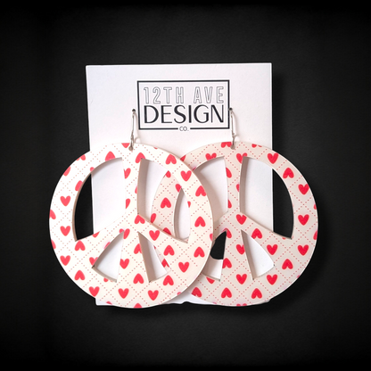 Peace sign earrings with heart pattern on a 12th Ave Design card against a black background